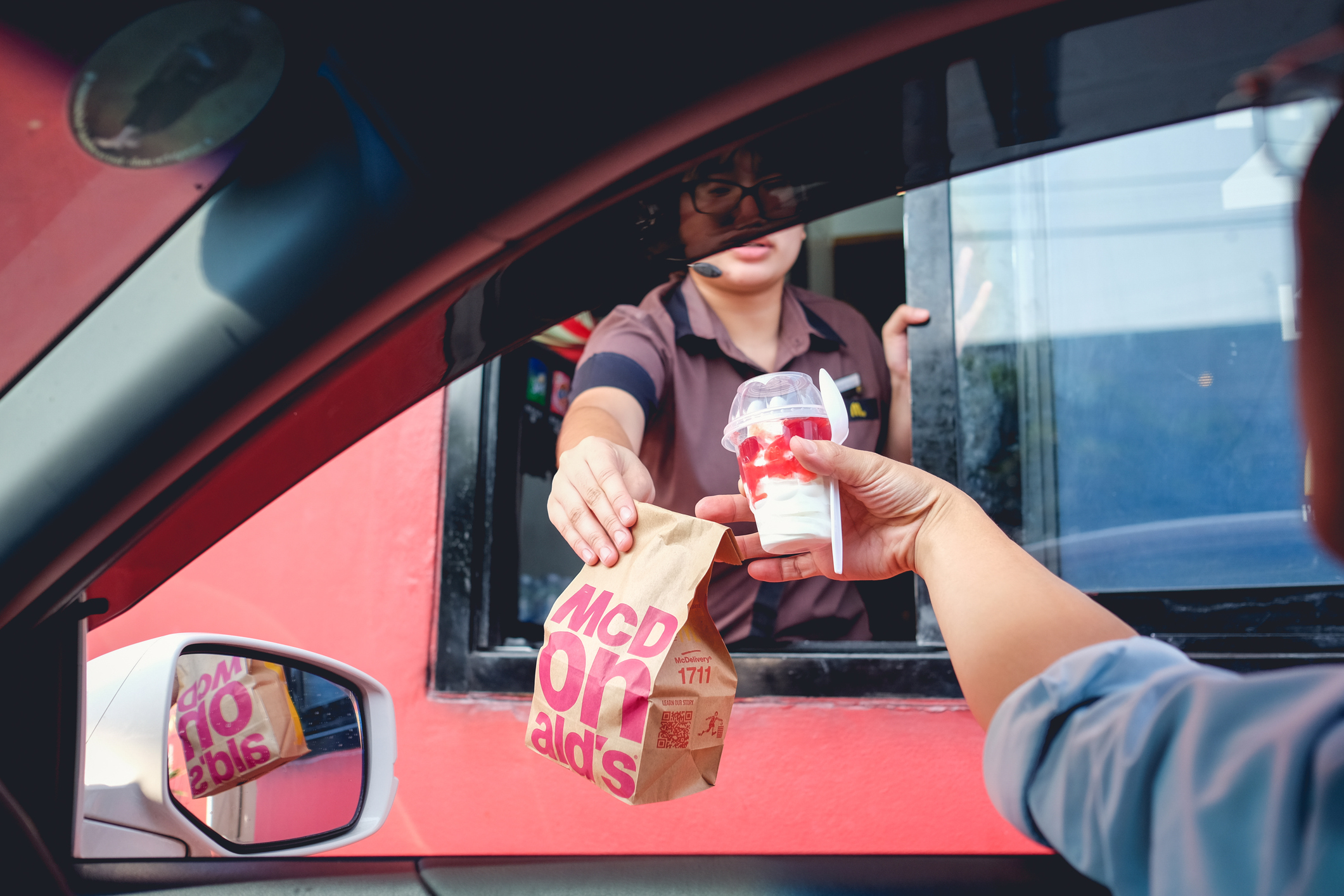 A McDonald’s crew member handing an order through the drive-thru window